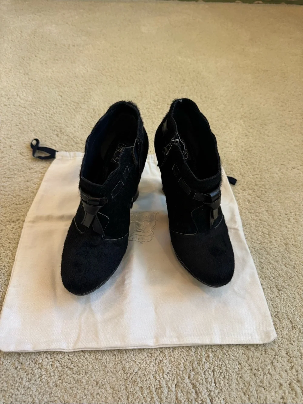 ZORAIDE black calf hair ankle booties with leather strap and tassel accents.